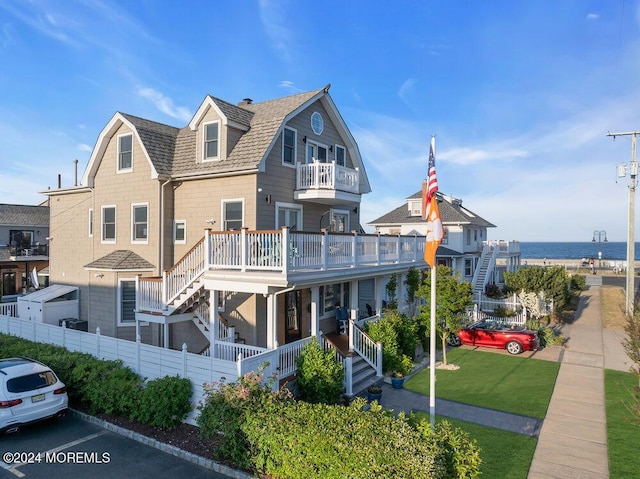 view of front of property with a front yard, a balcony, and covered porch