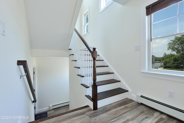 stairway with hardwood / wood-style flooring, baseboard heating, and a wealth of natural light