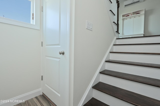 stairway featuring a wall mounted air conditioner and wood-type flooring