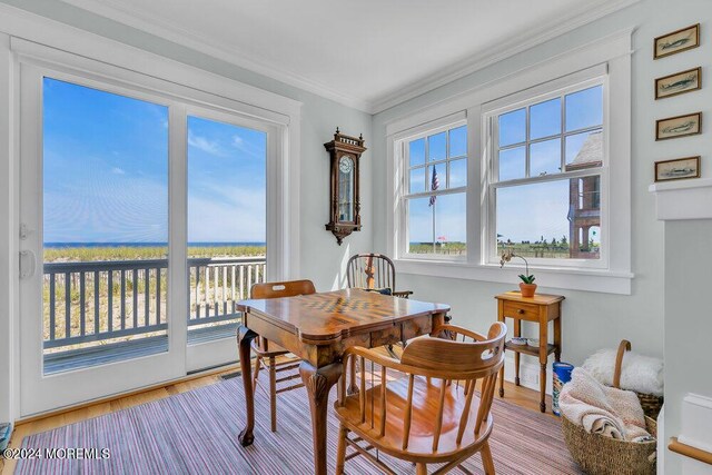 dining space featuring light hardwood / wood-style flooring, a water view, and ornamental molding