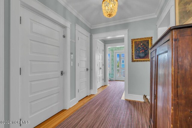 hall featuring hardwood / wood-style floors, crown molding, and a notable chandelier