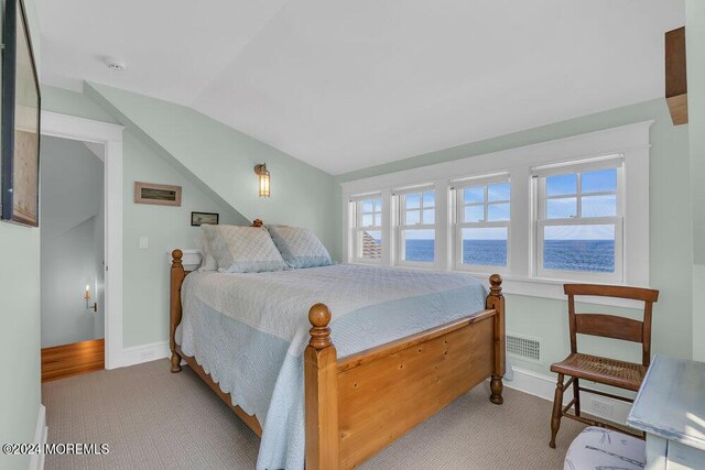 carpeted bedroom featuring a water view and vaulted ceiling