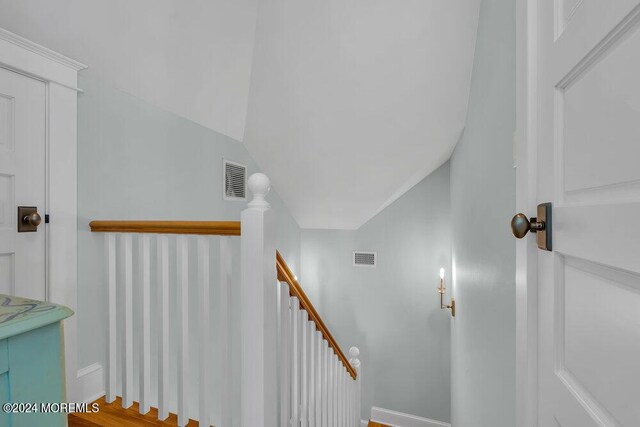 stairway featuring lofted ceiling and hardwood / wood-style flooring