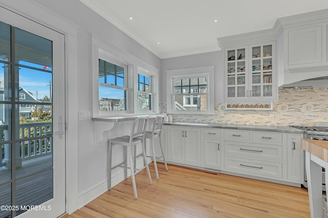 kitchen featuring light wood-type flooring, tasteful backsplash, white cabinetry, and ornamental molding