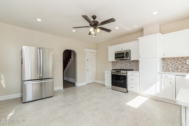 kitchen with ceiling fan, light tile patterned floors, white cabinetry, appliances with stainless steel finishes, and decorative backsplash