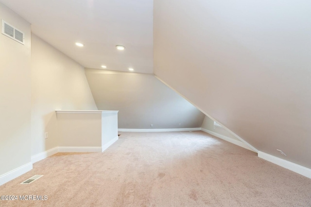 bonus room with vaulted ceiling and light carpet