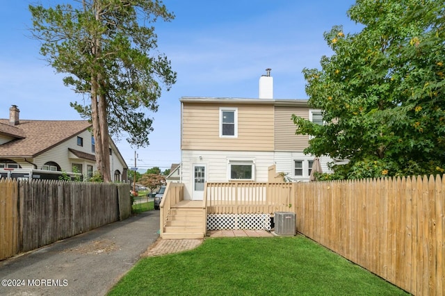 rear view of property with a lawn and central air condition unit