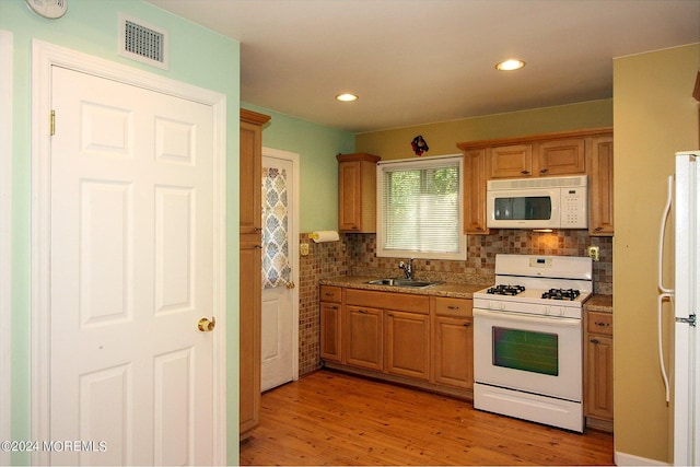 kitchen featuring decorative backsplash, white appliances, sink, and light hardwood / wood-style flooring