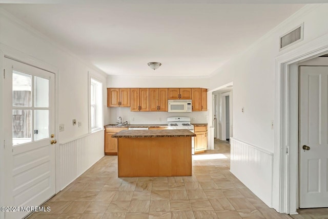 kitchen with ornamental molding, a kitchen island, and white appliances