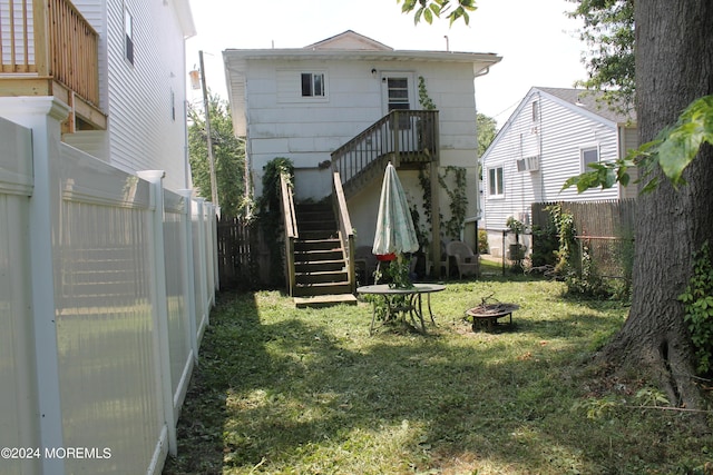 back of house with an outdoor fire pit and a yard