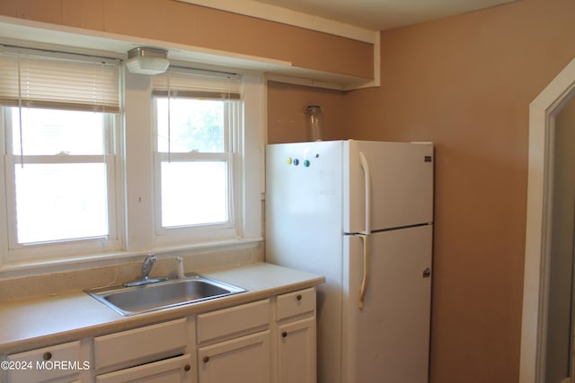 kitchen featuring white refrigerator, white cabinetry, and sink