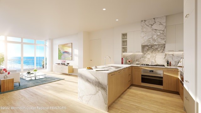 kitchen with appliances with stainless steel finishes, sink, white cabinets, decorative backsplash, and a water view