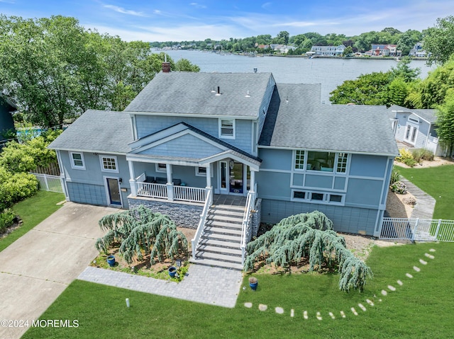 view of front of house featuring a water view, a garage, covered porch, and a front yard