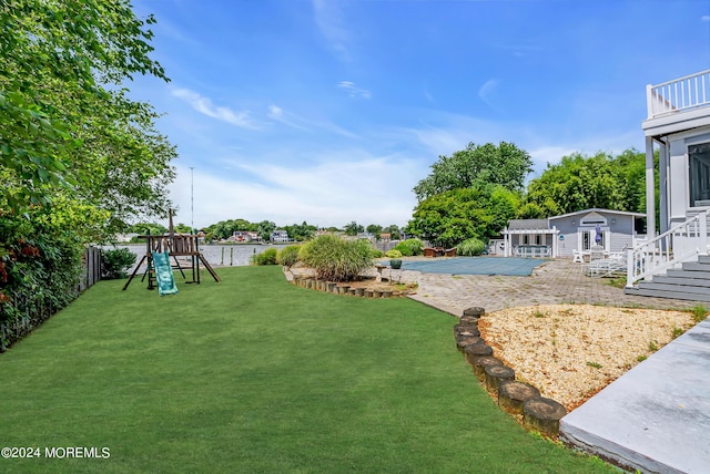 view of yard with a playground, a covered pool, a patio area, and a shed