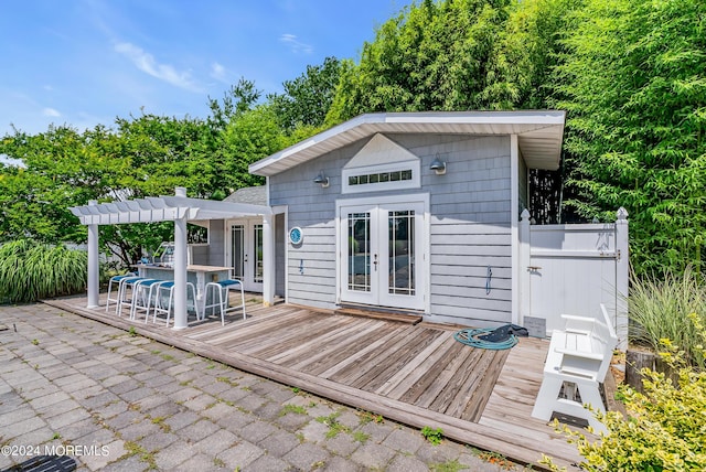 rear view of property with french doors, a wooden deck, a pergola, and a patio area