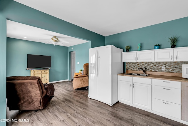 kitchen featuring sink, white cabinetry, hardwood / wood-style flooring, white refrigerator with ice dispenser, and backsplash