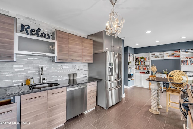 kitchen with sink, dark stone countertops, hanging light fixtures, stainless steel appliances, and tasteful backsplash