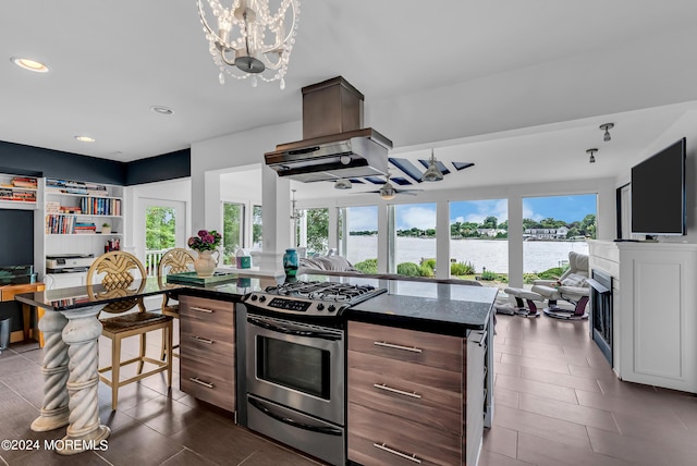 kitchen featuring stainless steel gas stove, a breakfast bar area, dark tile patterned flooring, a chandelier, and a center island