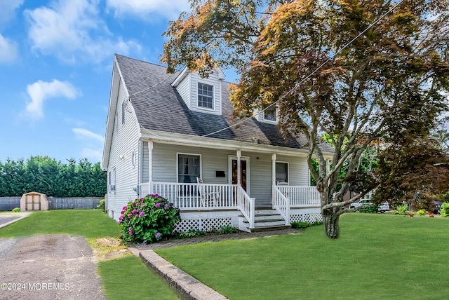 cape cod house with a shed, a front lawn, and covered porch