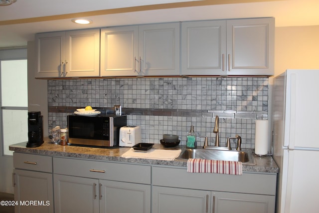 kitchen with white refrigerator, sink, backsplash, and gray cabinets