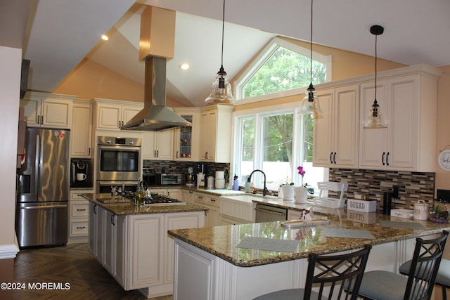 kitchen with stone countertops, hanging light fixtures, backsplash, stainless steel appliances, and a kitchen island