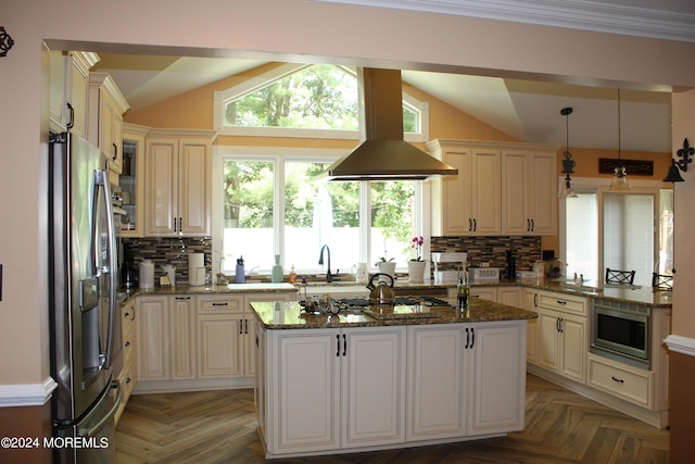 kitchen with lofted ceiling, appliances with stainless steel finishes, pendant lighting, dark stone counters, and a kitchen island with sink