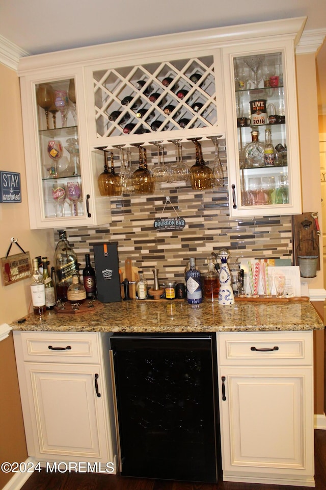 bar featuring wine cooler, backsplash, white cabinets, and stone counters