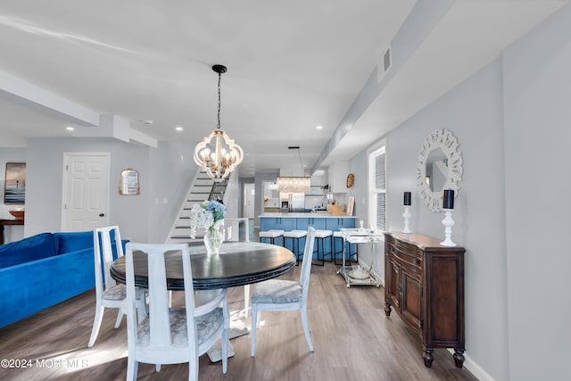 dining space with light wood-type flooring and an inviting chandelier