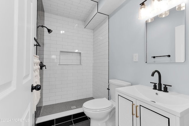 bathroom featuring tile patterned flooring, vanity, toilet, and a tile shower