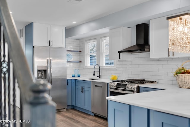 kitchen featuring stainless steel appliances, white cabinetry, wall chimney exhaust hood, and sink