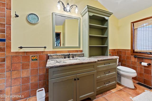 bathroom with tile patterned flooring, vanity, toilet, and tile walls