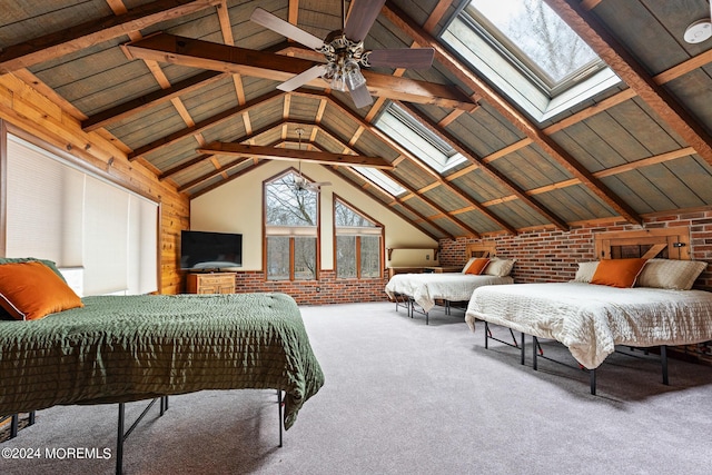 bedroom with vaulted ceiling with skylight, carpet flooring, ceiling fan, and brick wall