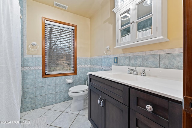 bathroom with tile patterned floors, vanity, tile walls, and toilet