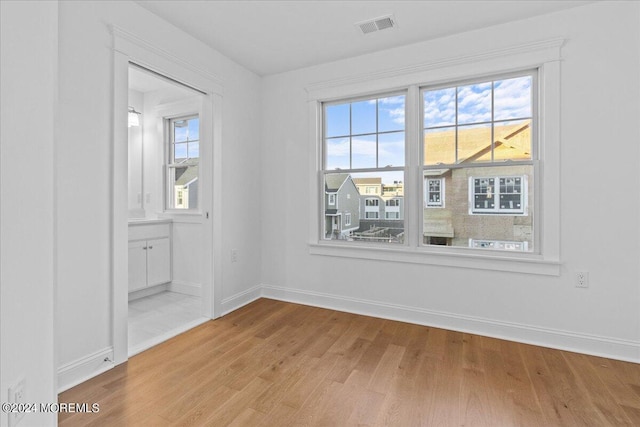 empty room featuring baseboards, light wood-style floors, and visible vents
