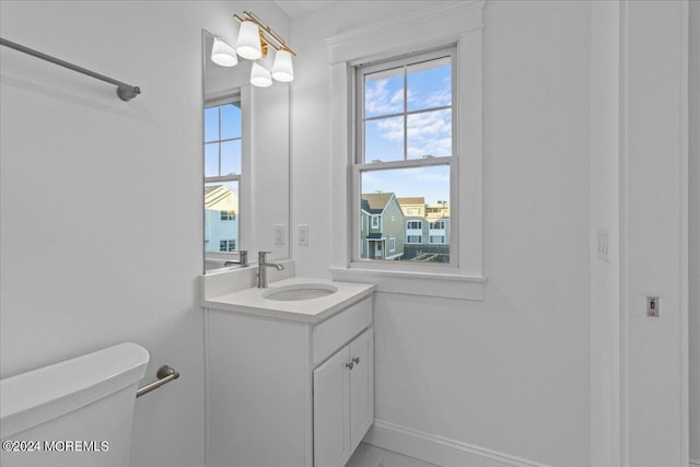 half bath featuring baseboards, toilet, and vanity