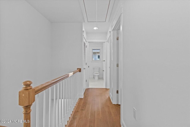 hallway featuring attic access, light wood finished floors, and an upstairs landing