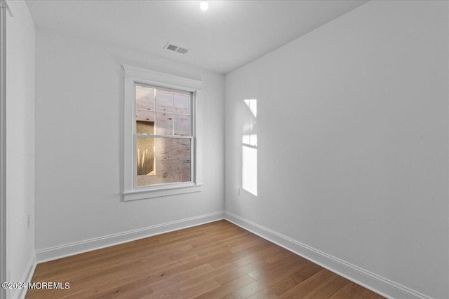 unfurnished room with baseboards, wood finished floors, and visible vents
