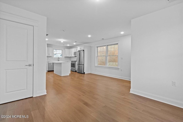 unfurnished living room featuring baseboards, light wood-type flooring, and recessed lighting