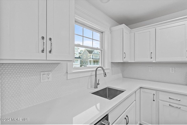 kitchen with light countertops, tasteful backsplash, white cabinetry, and a sink