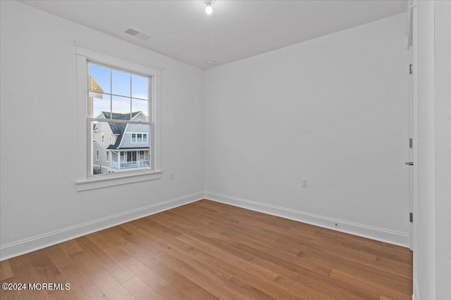 empty room featuring baseboards, wood finished floors, and visible vents