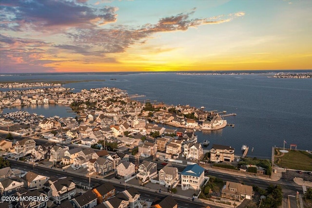 aerial view at dusk featuring a residential view and a water view