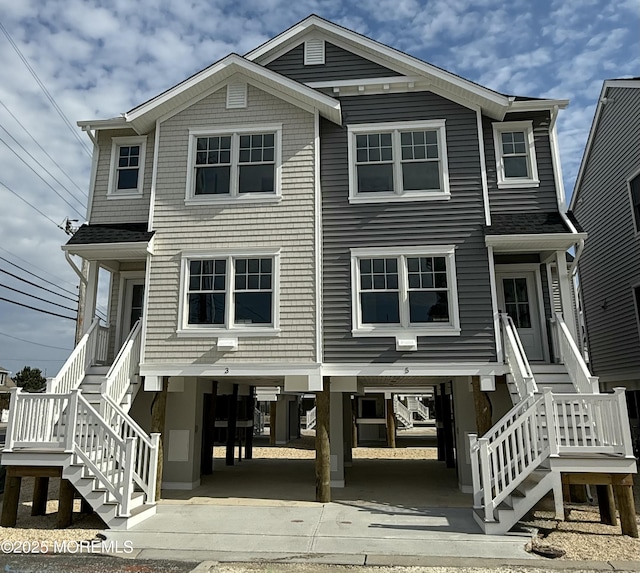 rear view of property featuring a carport and stairway
