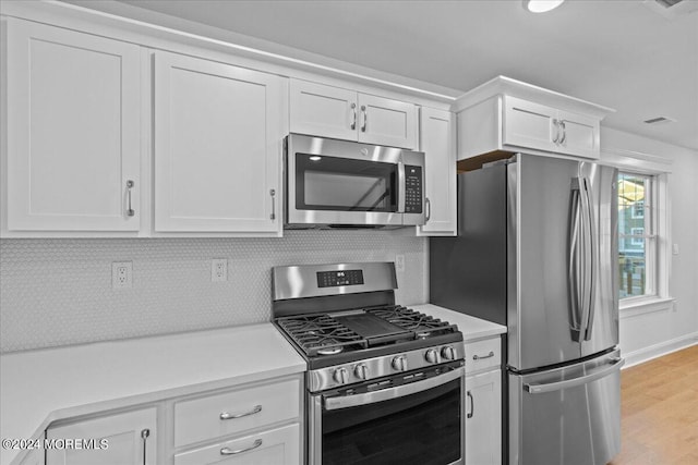 kitchen with tasteful backsplash, stainless steel appliances, light wood-type flooring, and white cabinets