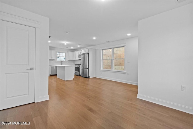 unfurnished living room with sink and light wood-type flooring