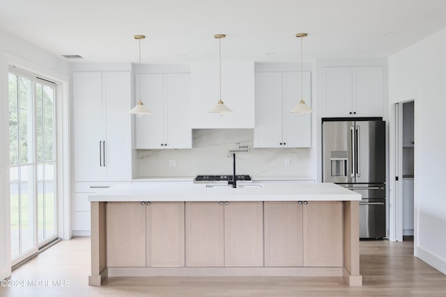 kitchen with tasteful backsplash, a center island with sink, light hardwood / wood-style floors, white cabinetry, and high end fridge