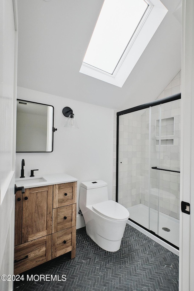 bathroom featuring toilet, a shower with shower door, vaulted ceiling with skylight, tile patterned flooring, and vanity