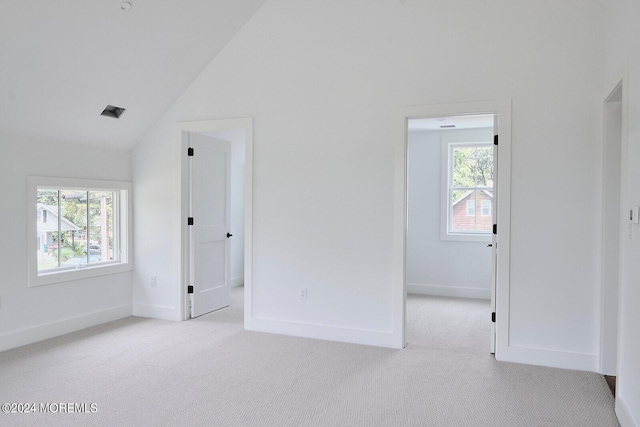 carpeted spare room featuring lofted ceiling and a healthy amount of sunlight