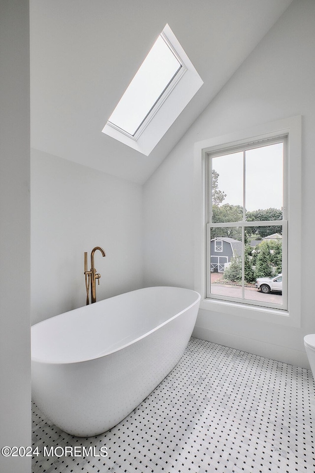 bathroom with vaulted ceiling with skylight and a washtub