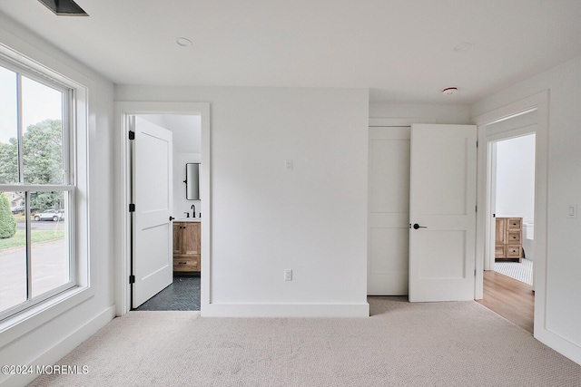 unfurnished bedroom featuring carpet floors, ensuite bath, and sink