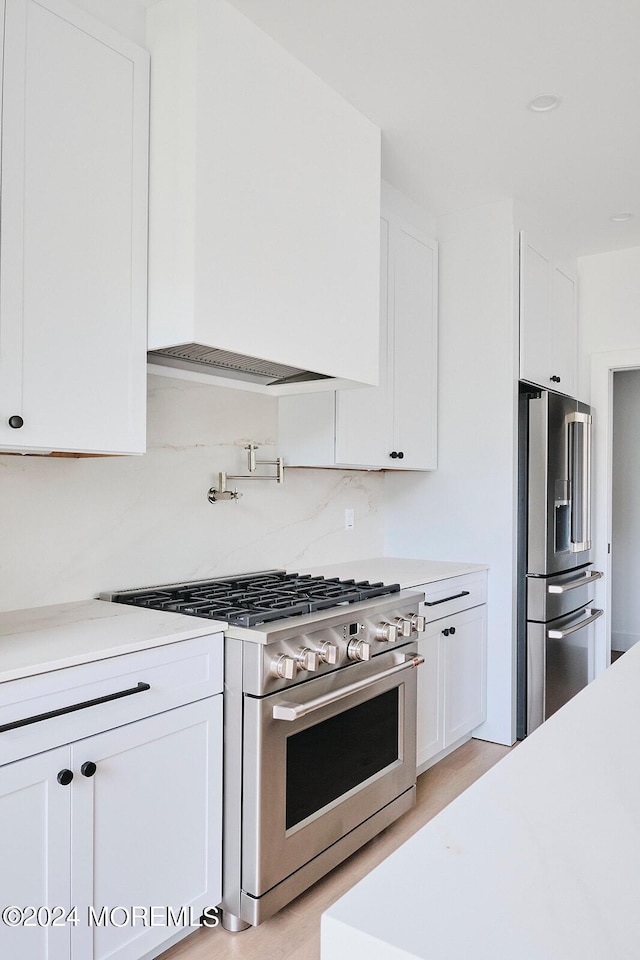 kitchen with light hardwood / wood-style floors, backsplash, stainless steel appliances, and white cabinetry